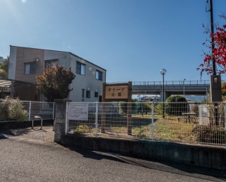 フェンスに囲まれた敷地に建物があり、入口に案内看板が設置された亀岡平和台周辺の公共施設の外観